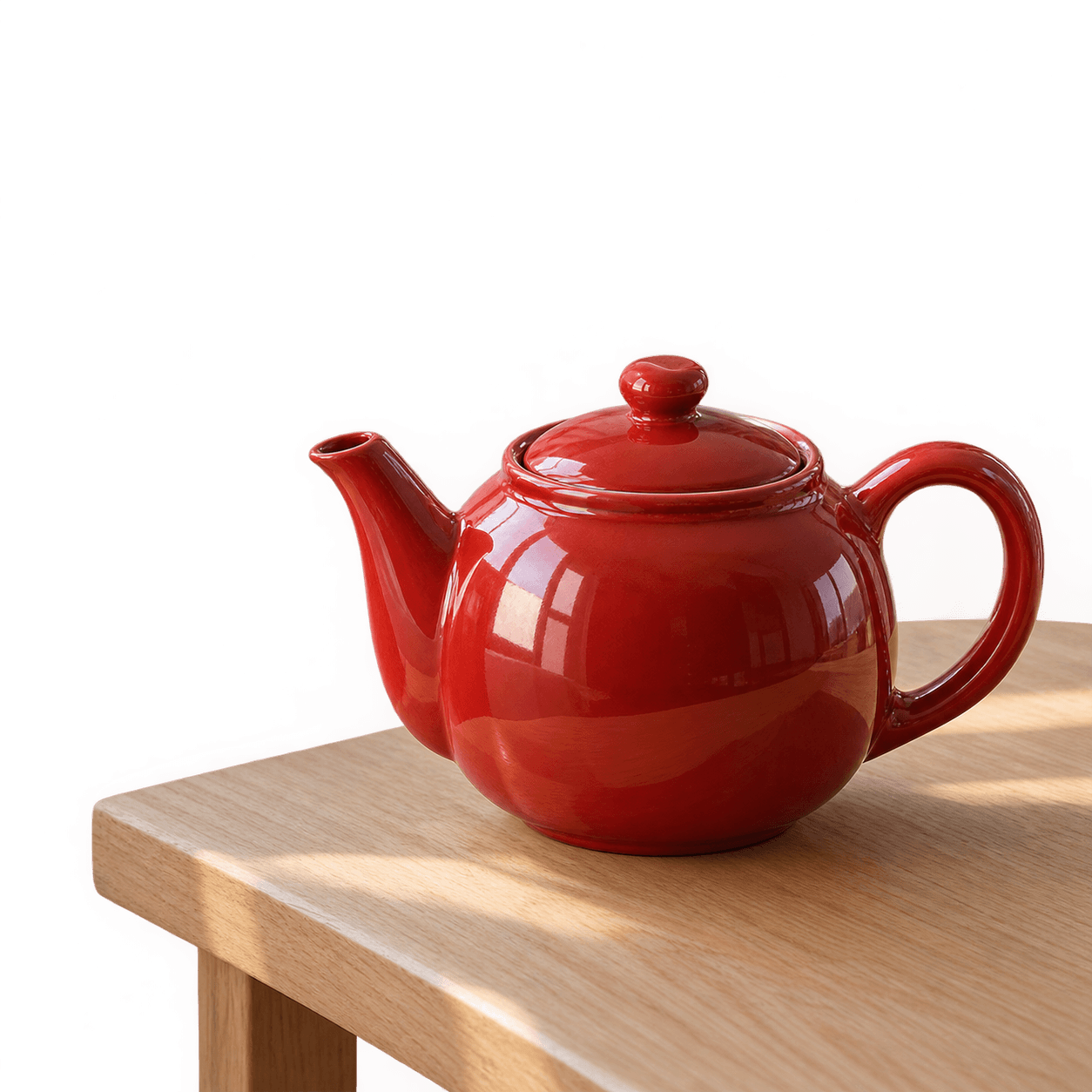 A glossy red ceramic teapot rests on part of a pale wooden table. The surrounding background is transparent.